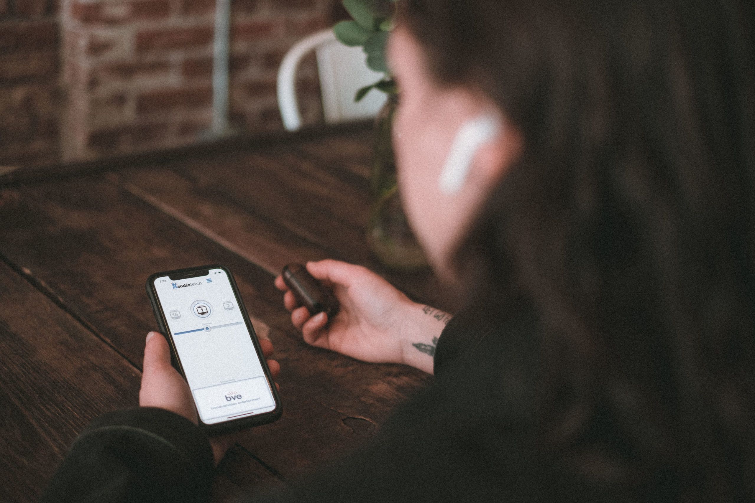 Woman Using AudioFetch App in Restaurant - Wireless Audio Streaming