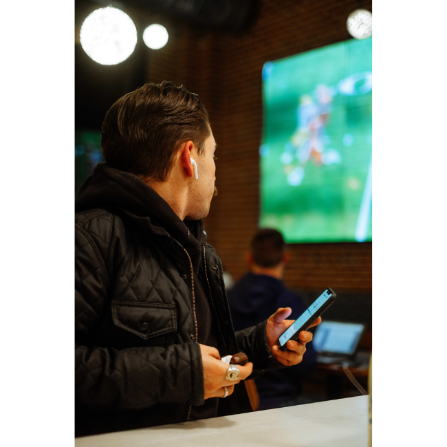 Man Using AudioFetch App at Sports Bar