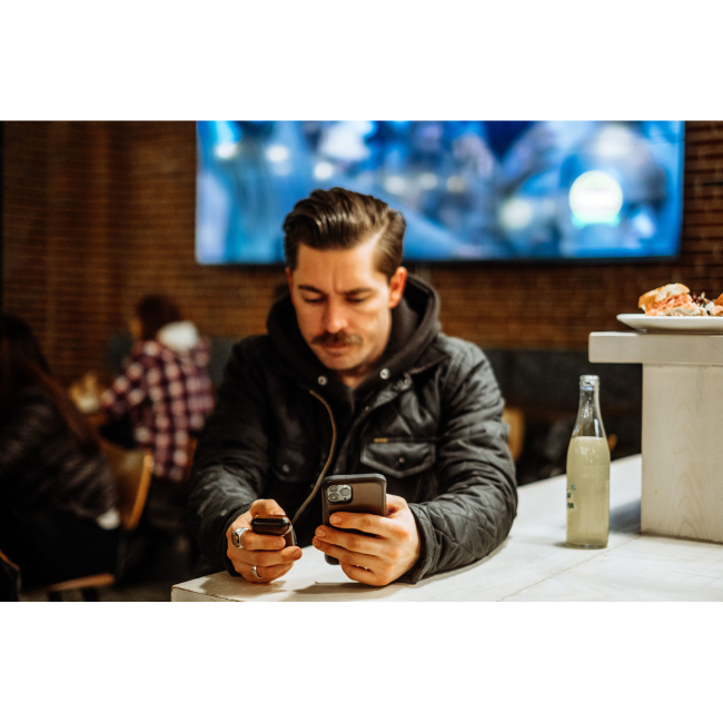 Man Using AudioFetch App in a Sports Bar